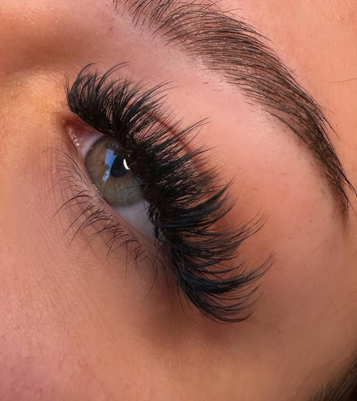 Whispy-Wimpern mit längeren Spikes und fluffiger Textur an einem grünen Auge